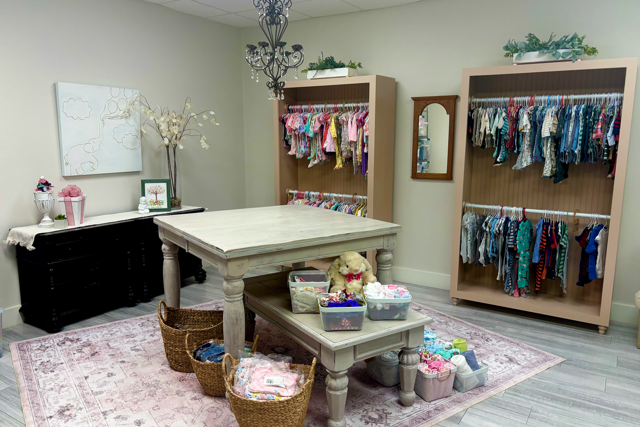 Salesperson with couple buying baby clothes in shop